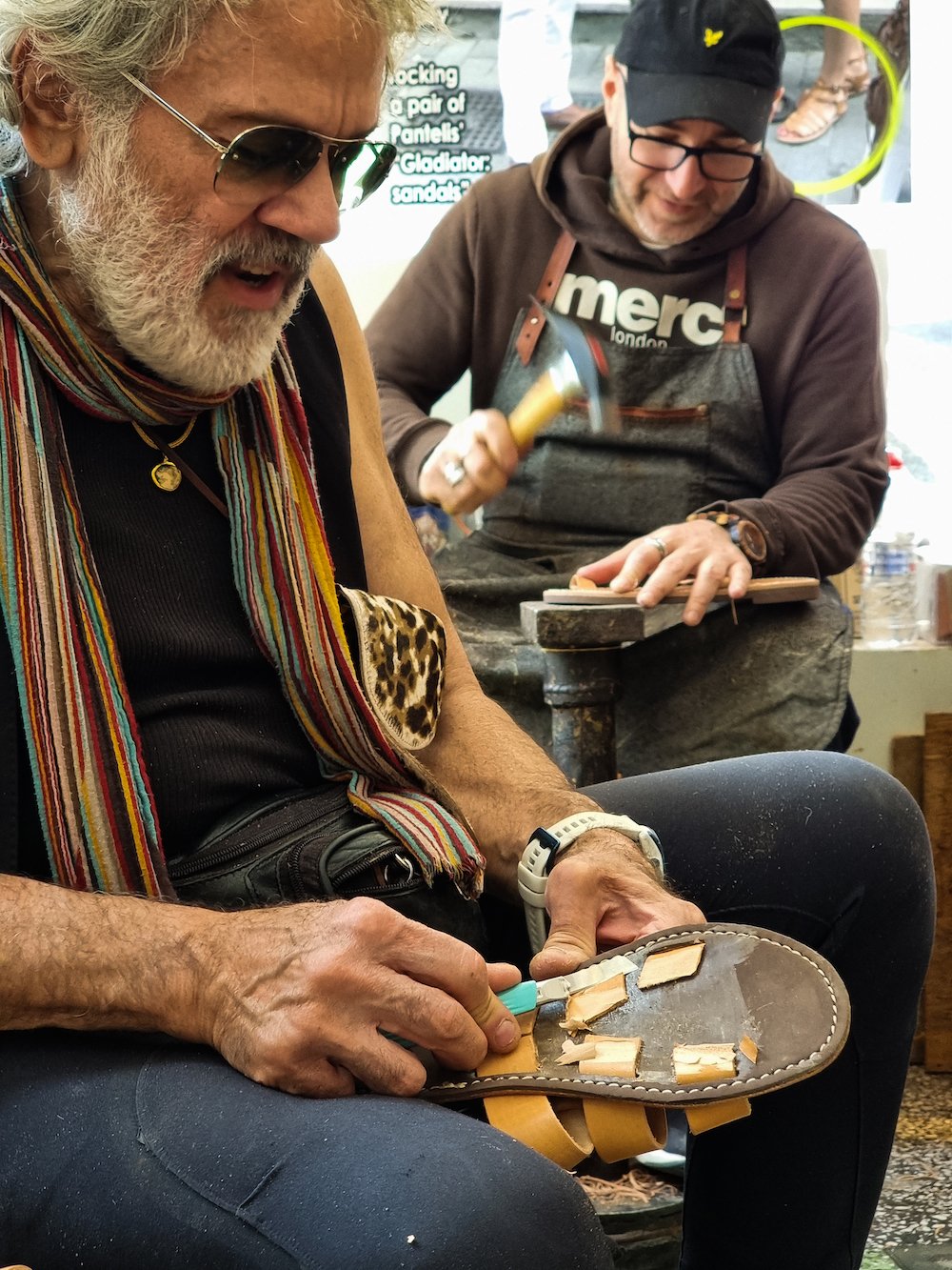 A man is working on a pair of Greek souvenir shoes, available to buy in Greece.