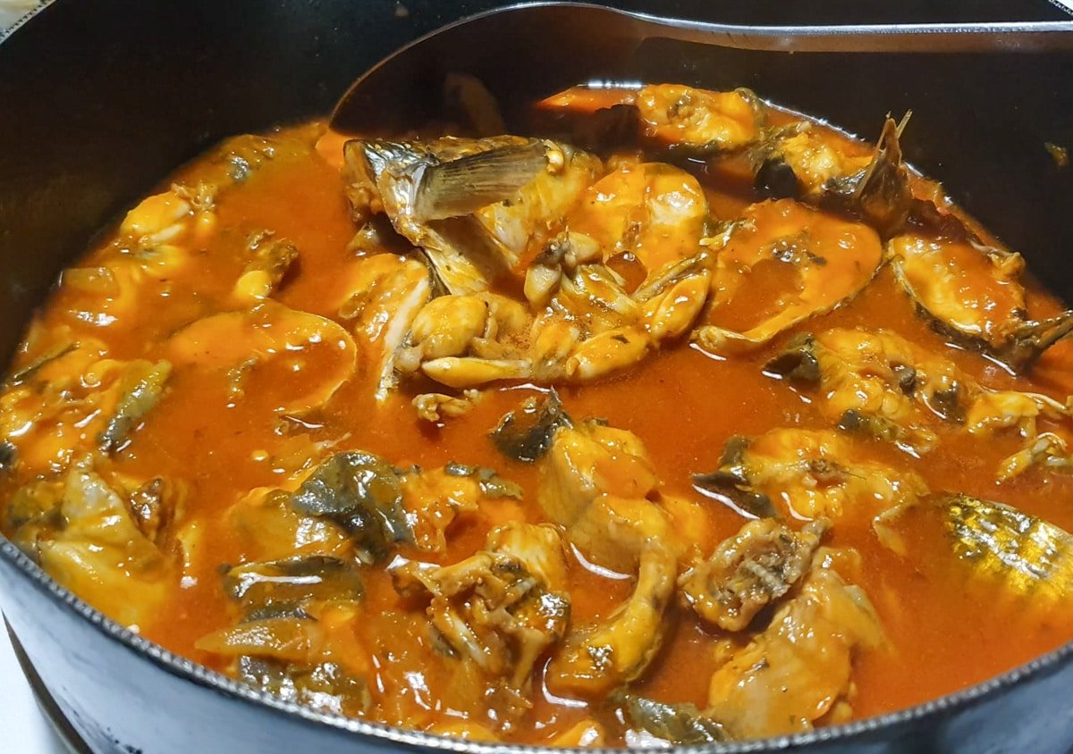 A pot of Neretvanski Brudet S Žabama i Jeguljama (Neretva Fish Stew With Frogs And Eels) simmering on the stove.