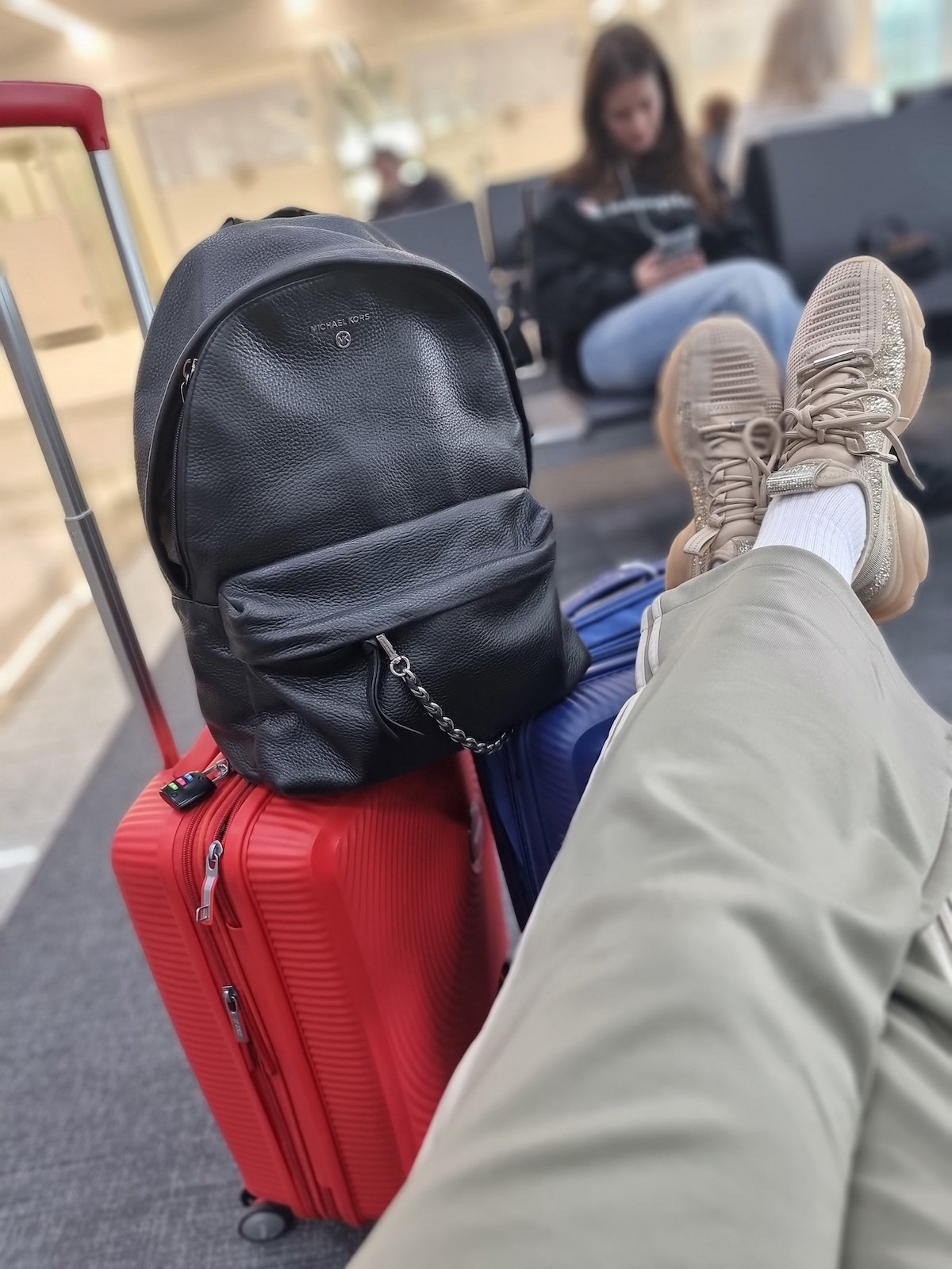 SJ's feet on luggage sitting on the floor at an airport before a long haul flight.