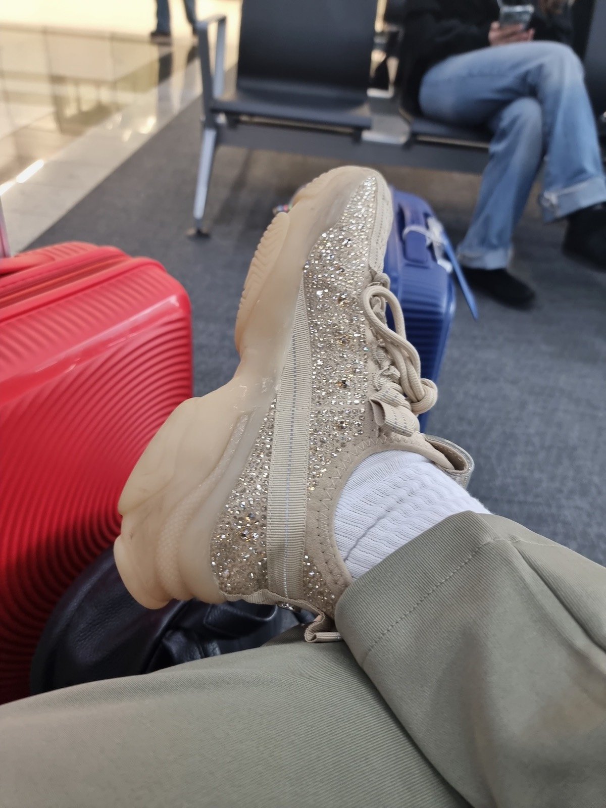 SJ's feet sitting next to luggage after a long haul flight at an airport.