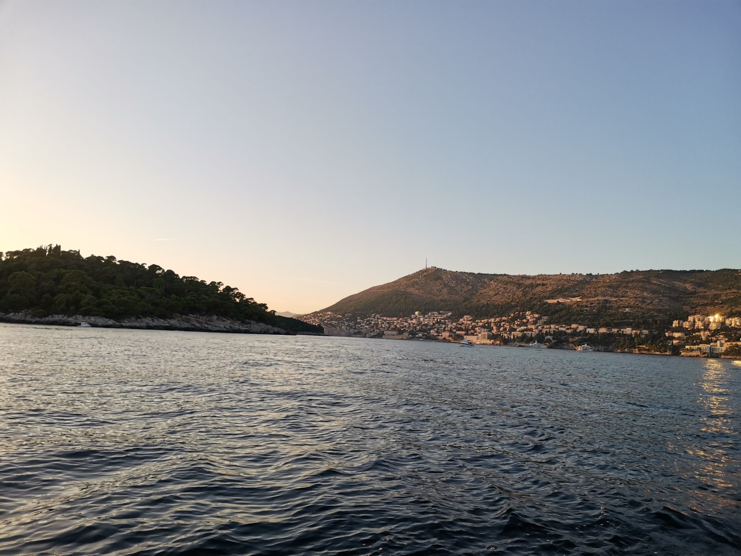 A picturesque view of a sparkling body of water with a lush hill in the background, capturing the essence of Croatia in spring.