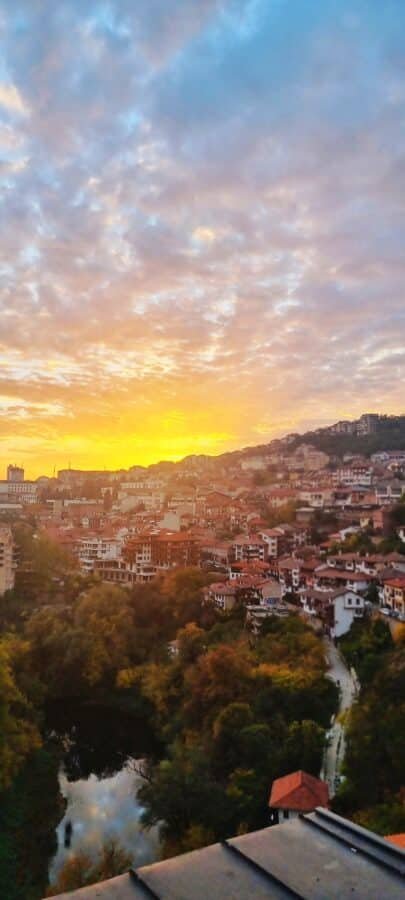 Enjoy the mesmerizing sunset over a cityscape with a serene river in the background while exploring things to do in Veliko Tarnovo.